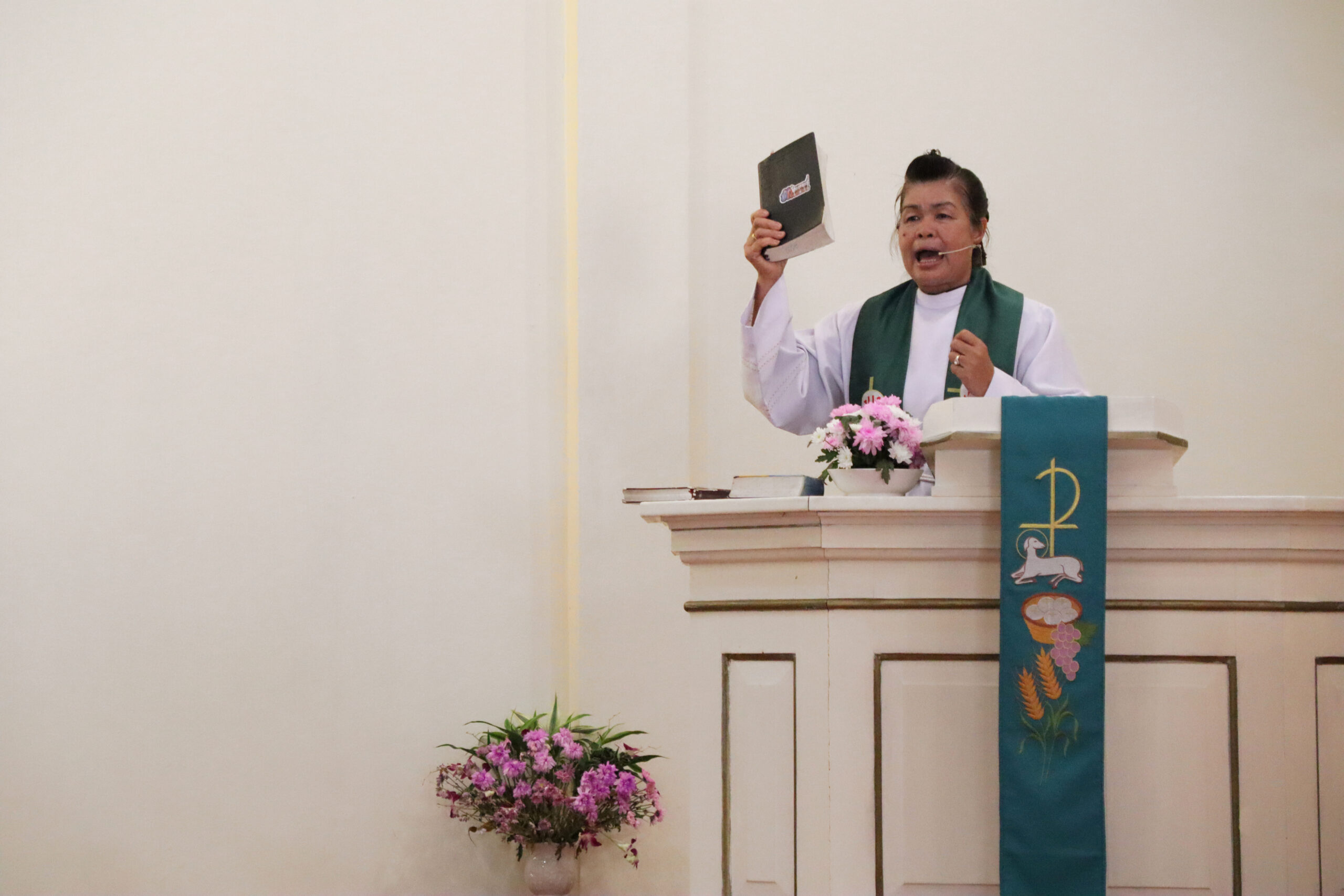Pastori saarnaamassa jumalanpalveluksessa kädessään Raamattu.