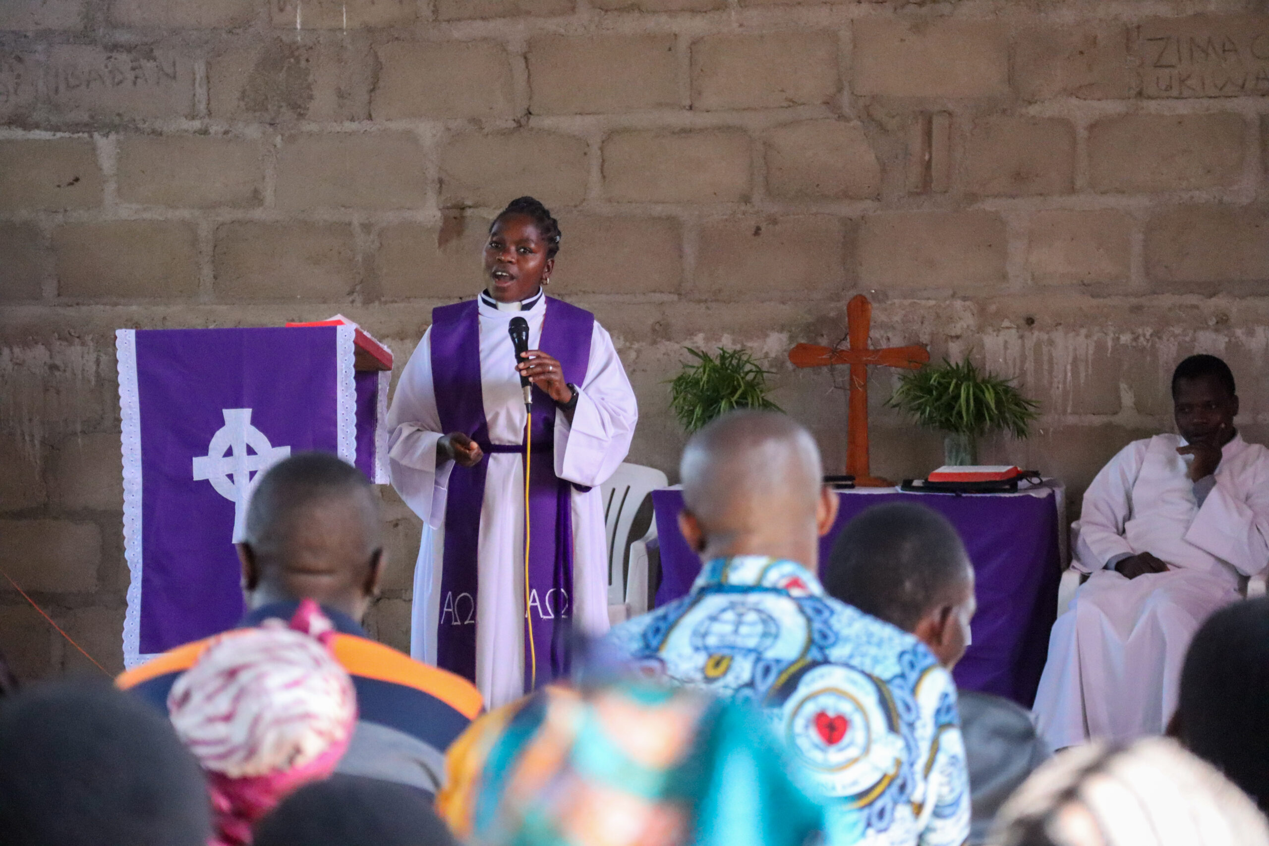 A pastor preaches in a church, with an altar cross in the background