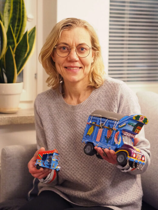 Nainen esittelee kuvaajalle värikästä kuorma-autoa.